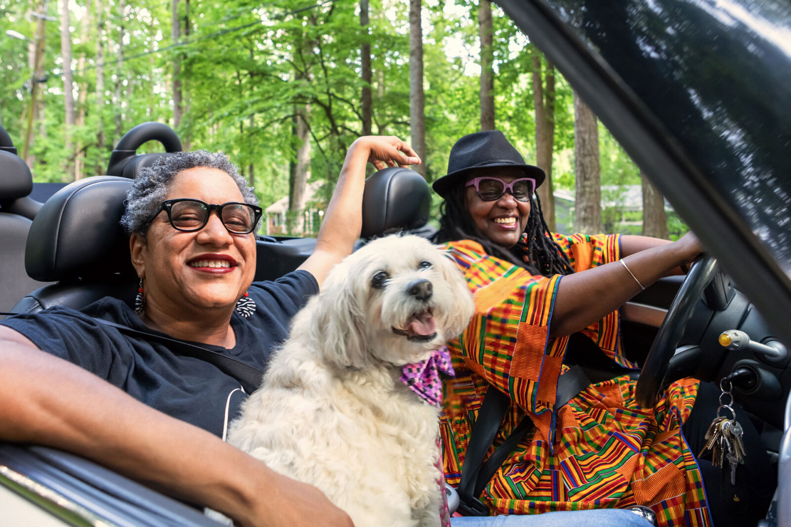 Women in convertible car with dog on lap